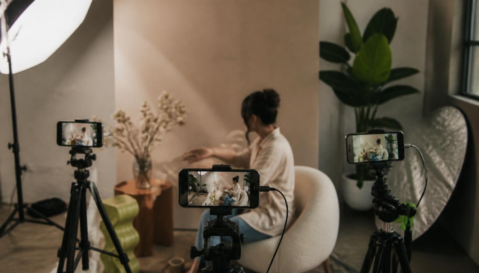 Phones on tripods recording a creator from three angles